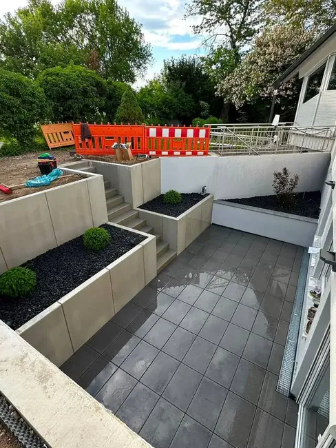 Fertige Terrassenanlage mit Stützmauern, Treppe und angelegten Beeten