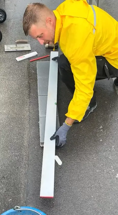 Stanko Petrovic richtet eine Pflasterfläche mit der Wasserwaage aus